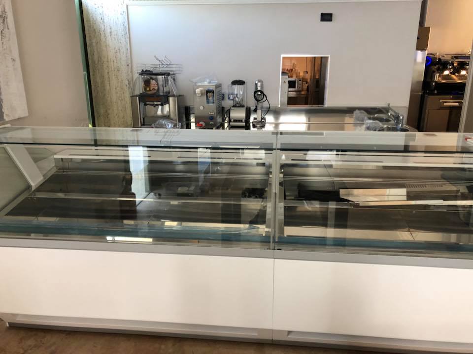 Vetrina vuota in un negozio, con attrezzature sul bancone posteriore.