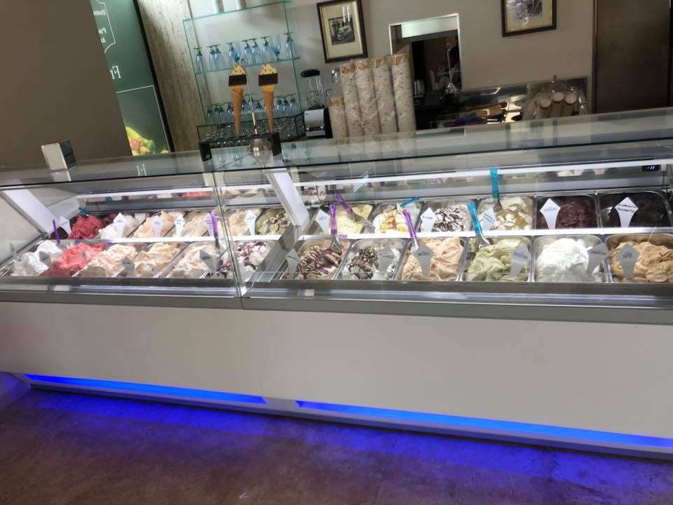 Vetrina per gelati con vari gusti di gelato, illuminata con luce blu.