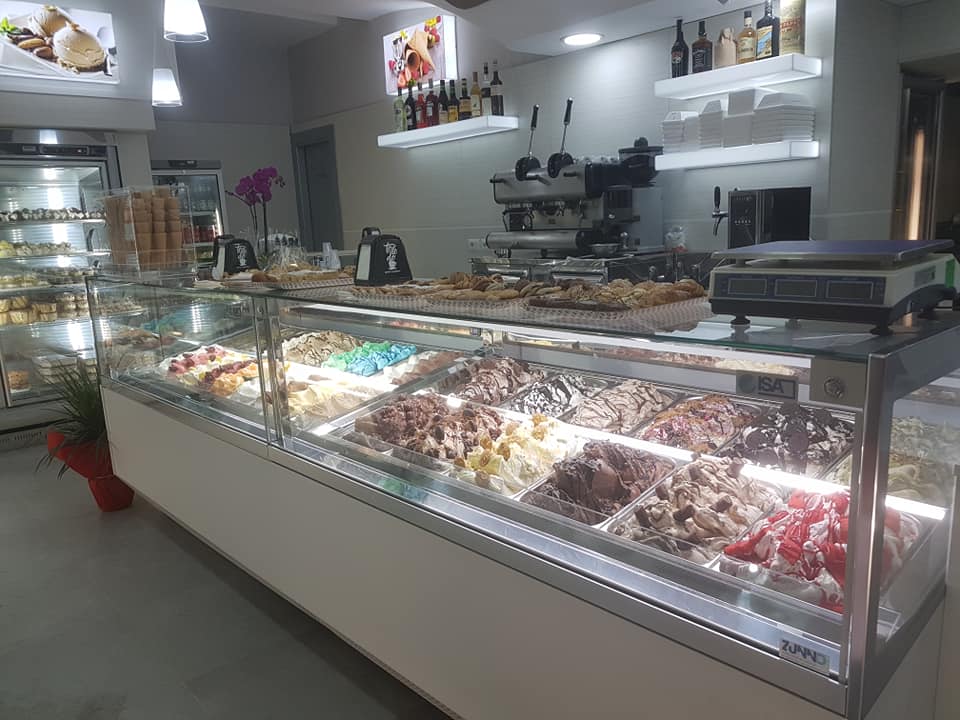 Interno di una gelateria con una vetrina piena di gelato colorato.