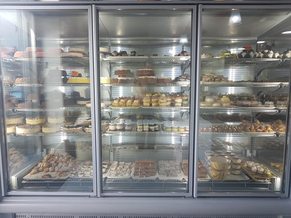 Vetrina refrigerata a tre ante piena di pasticcini e torte.