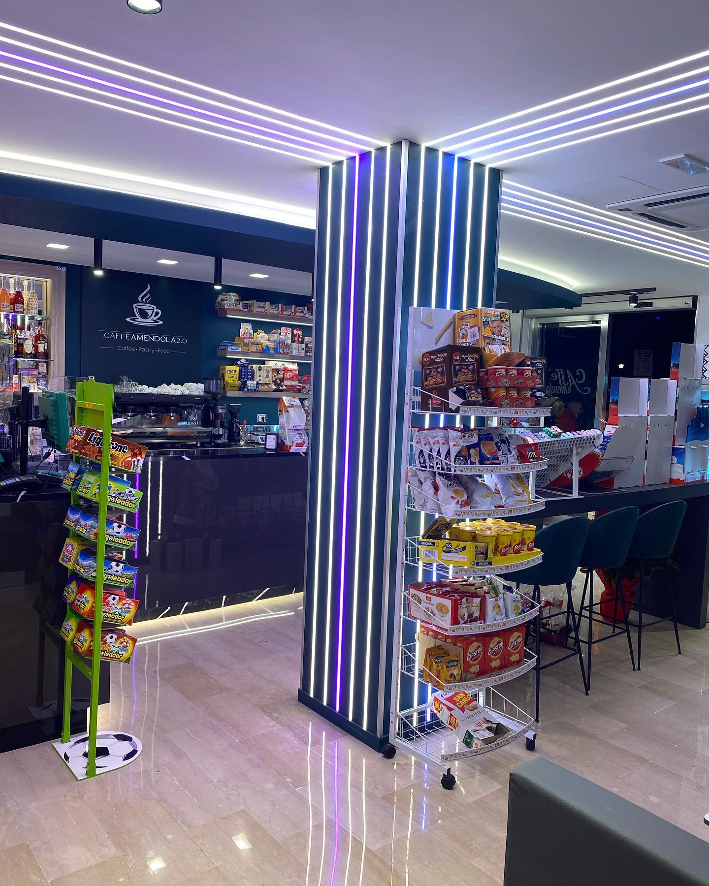 Interno di un bar con esposizione di snack. Una colonna con strisce e luci.