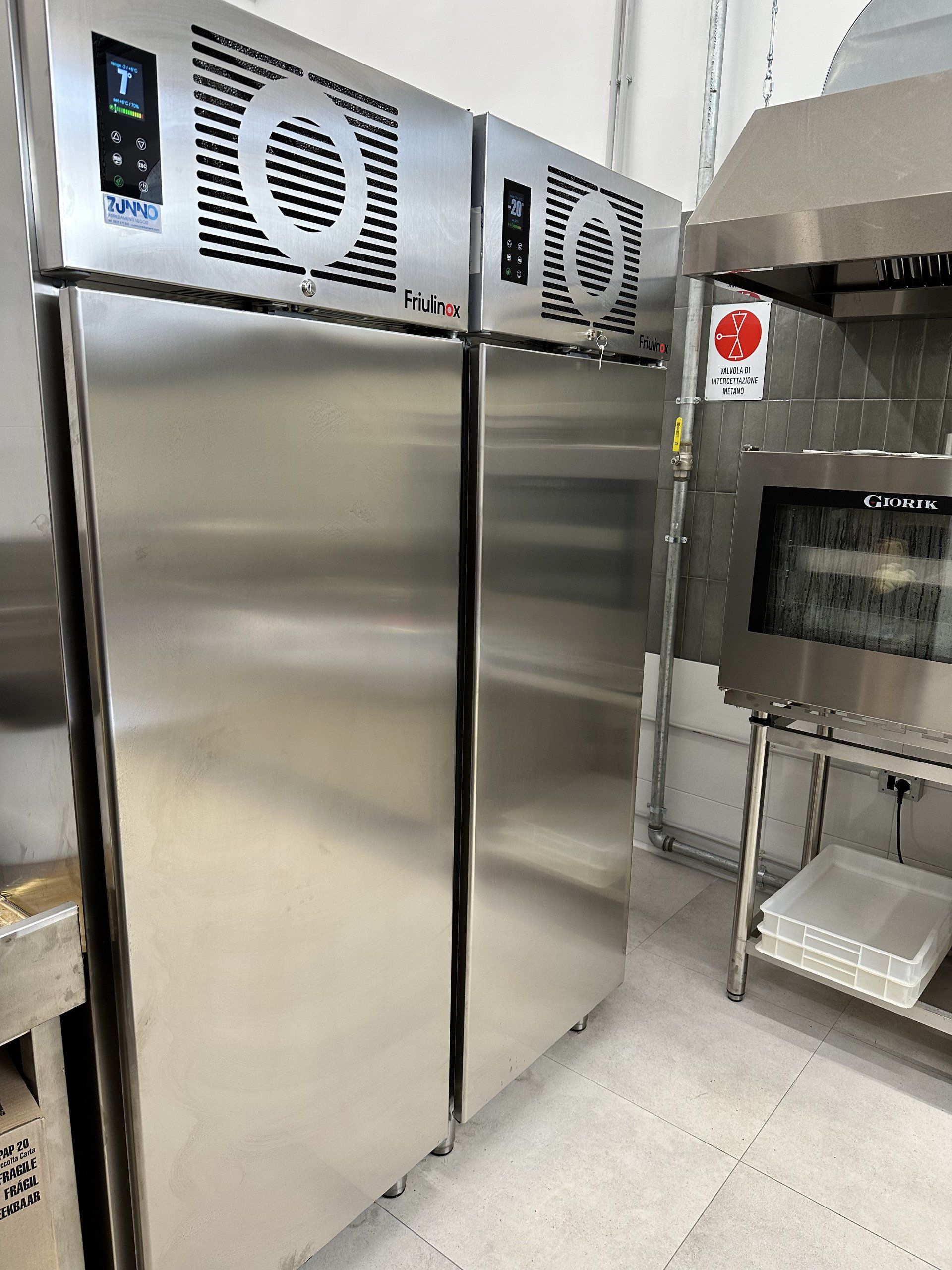 Frigorifero commerciale e forno in acciaio inox in una cucina.