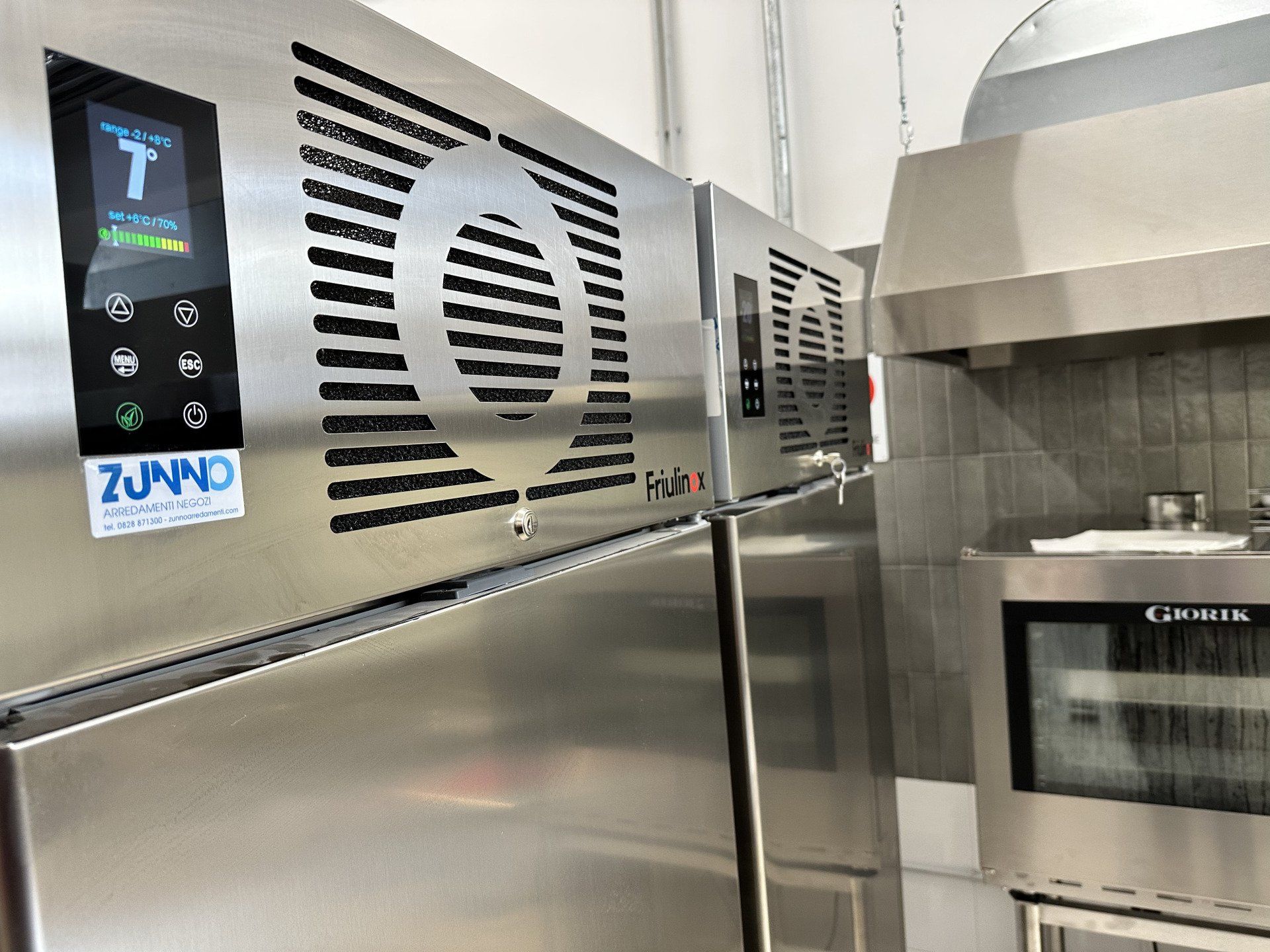 Attrezzatura da cucina commerciale in acciaio inossidabile, tra cui forno e congelatore con display digitali.