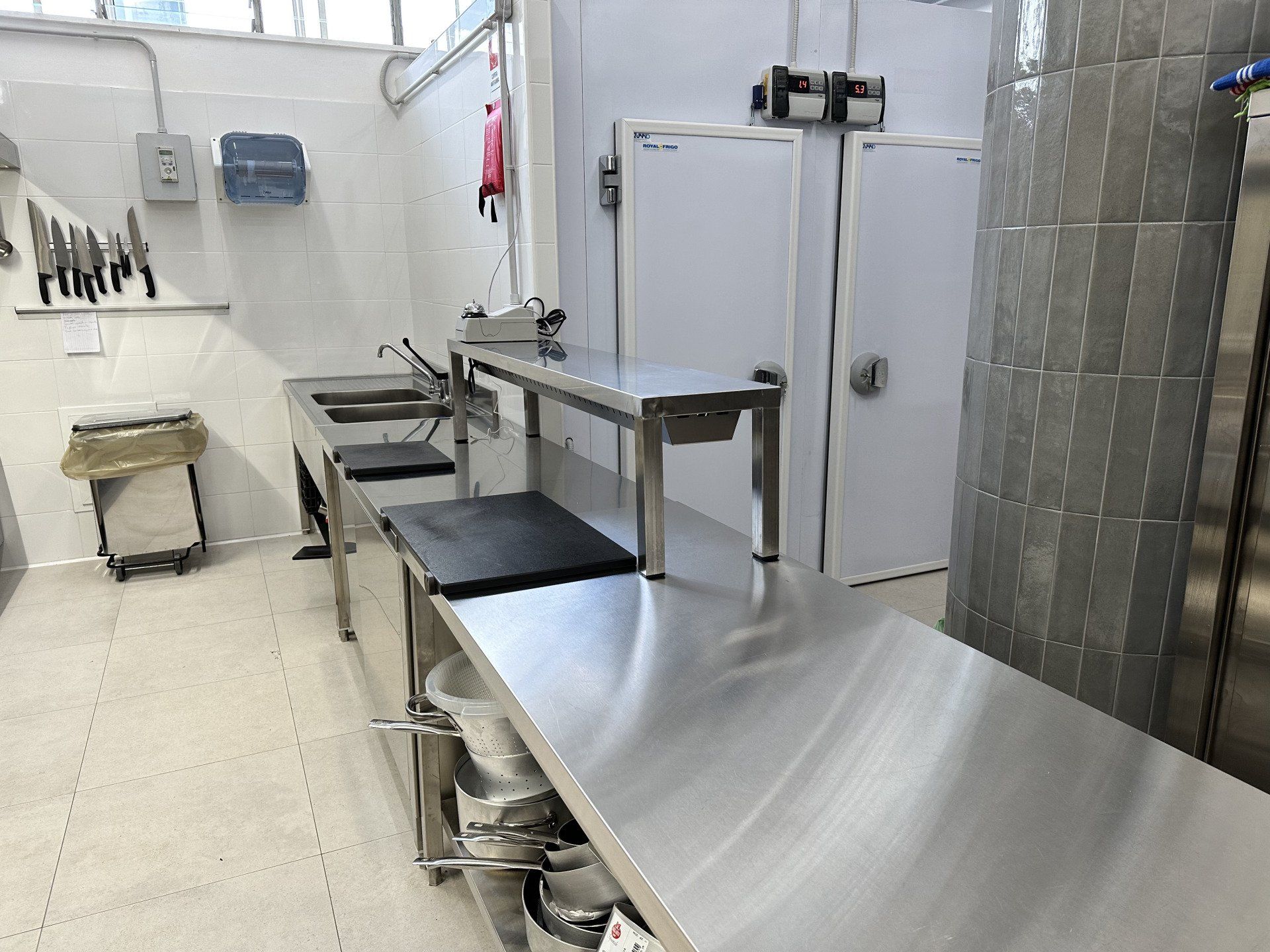 Cucina commerciale in acciaio inox con ripiani, elettrodomestici e portacoltelli.
