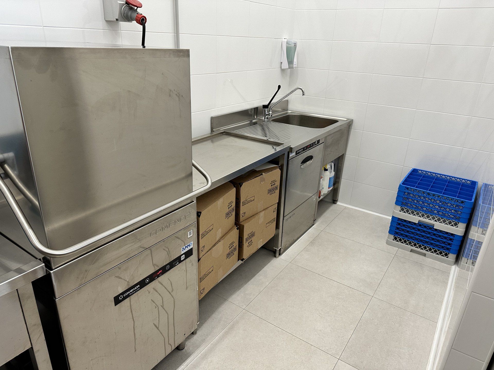 Cucina in acciaio inox con lavastoviglie, lavello, scatole e casse blu.