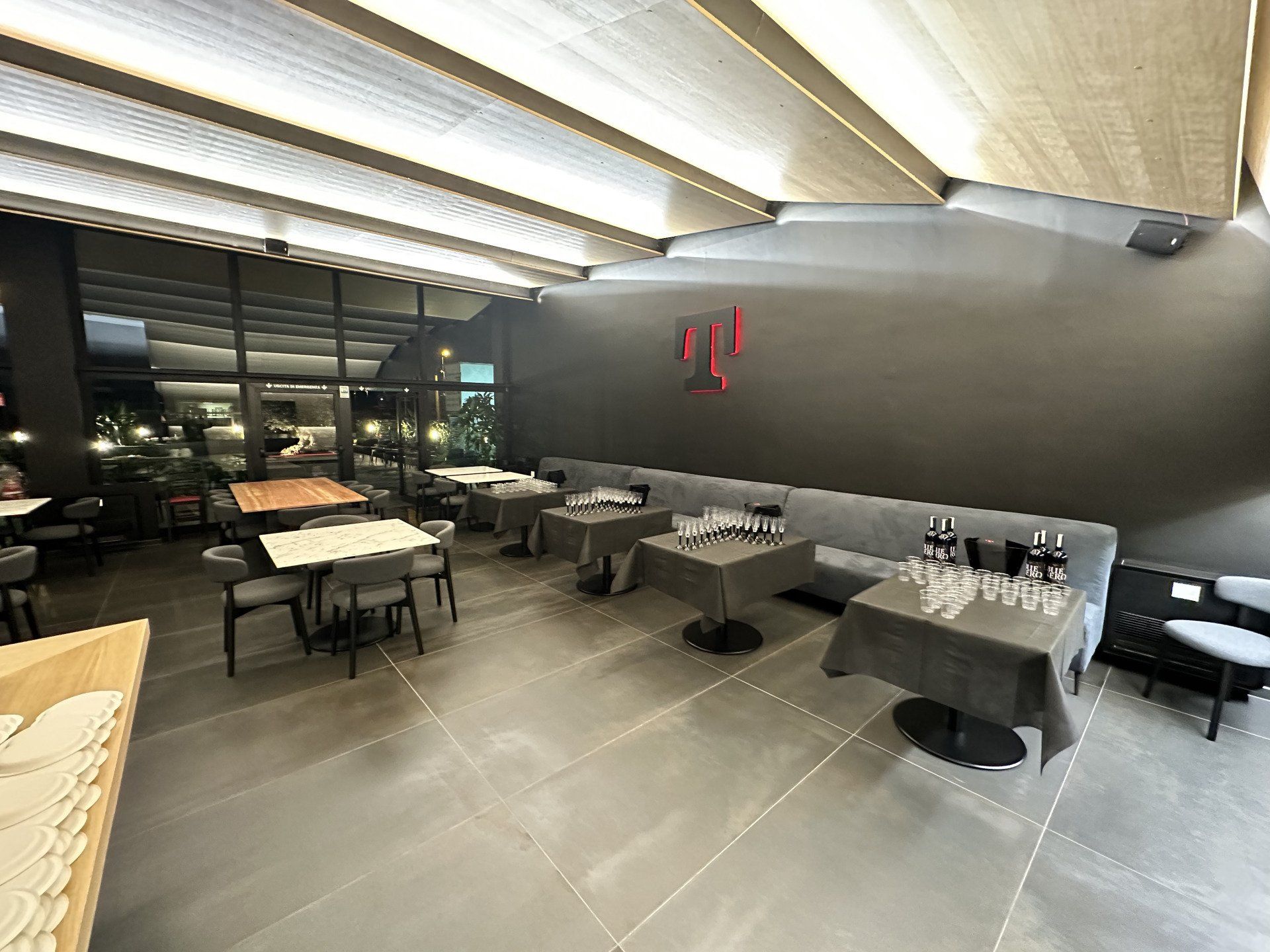 Interno di un negozio T-Mobile, con tavoli apparecchiati per il servizio e il logo dell'azienda su una parete scura.