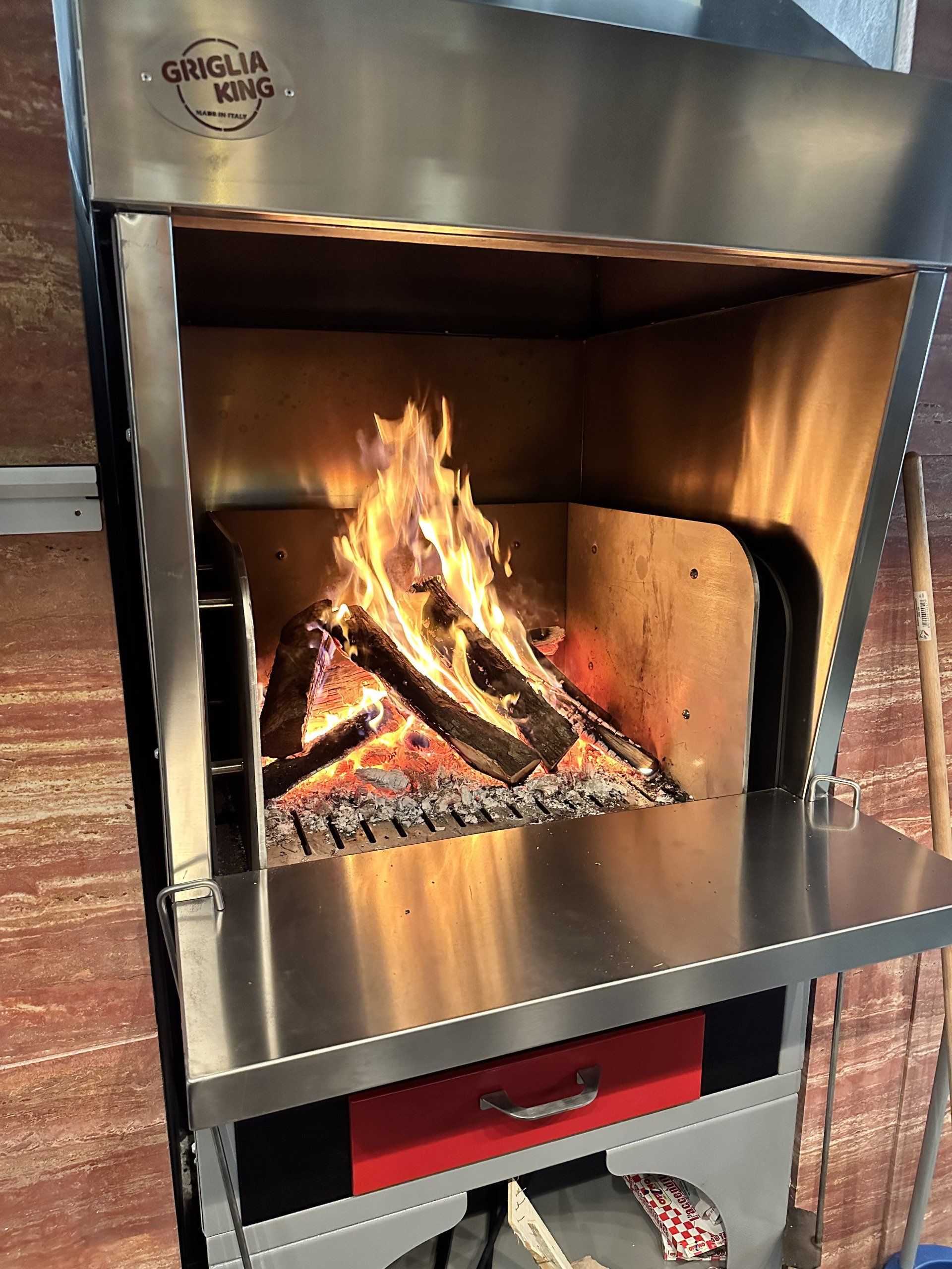 Griglia in acciaio inox con fuoco scoppiettante all'interno.