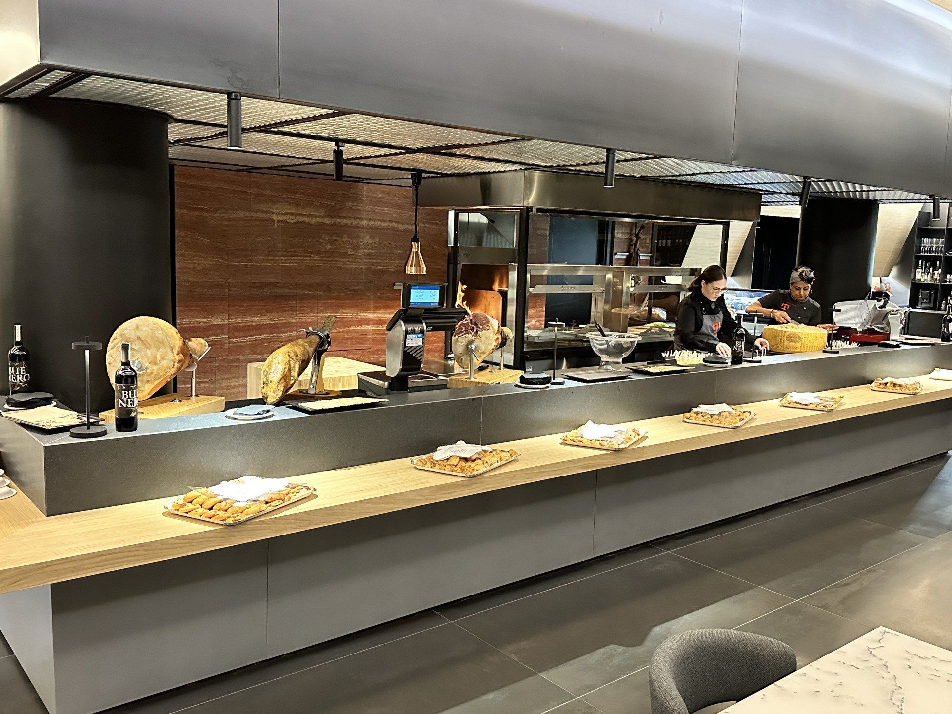 Bancone del ristorante con esposizione del cibo e due persone che preparano il cibo.