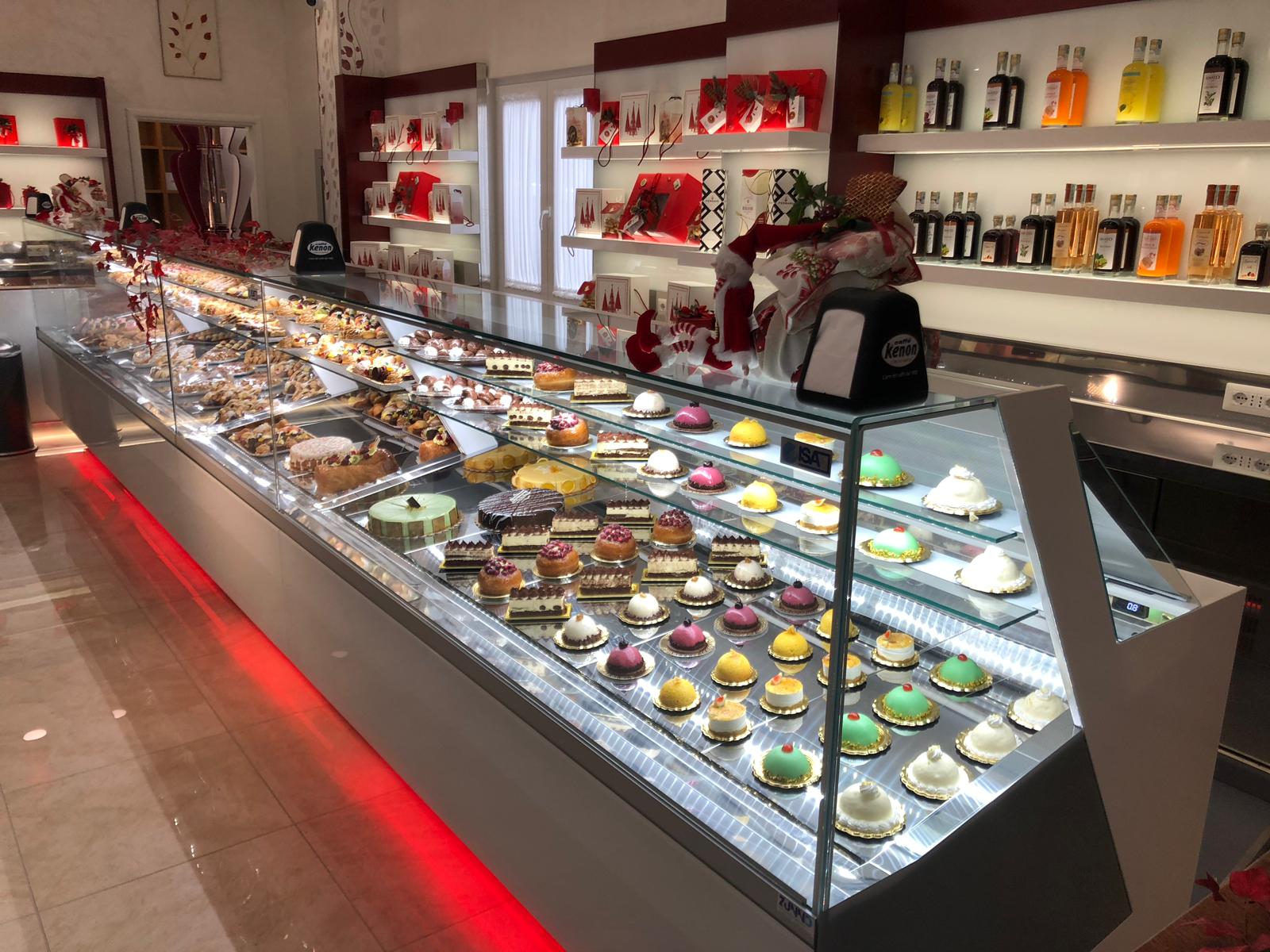 Una vetrina da pasticceria piena di pasticcini, torte e dolci colorati. Illuminata con luci a LED.