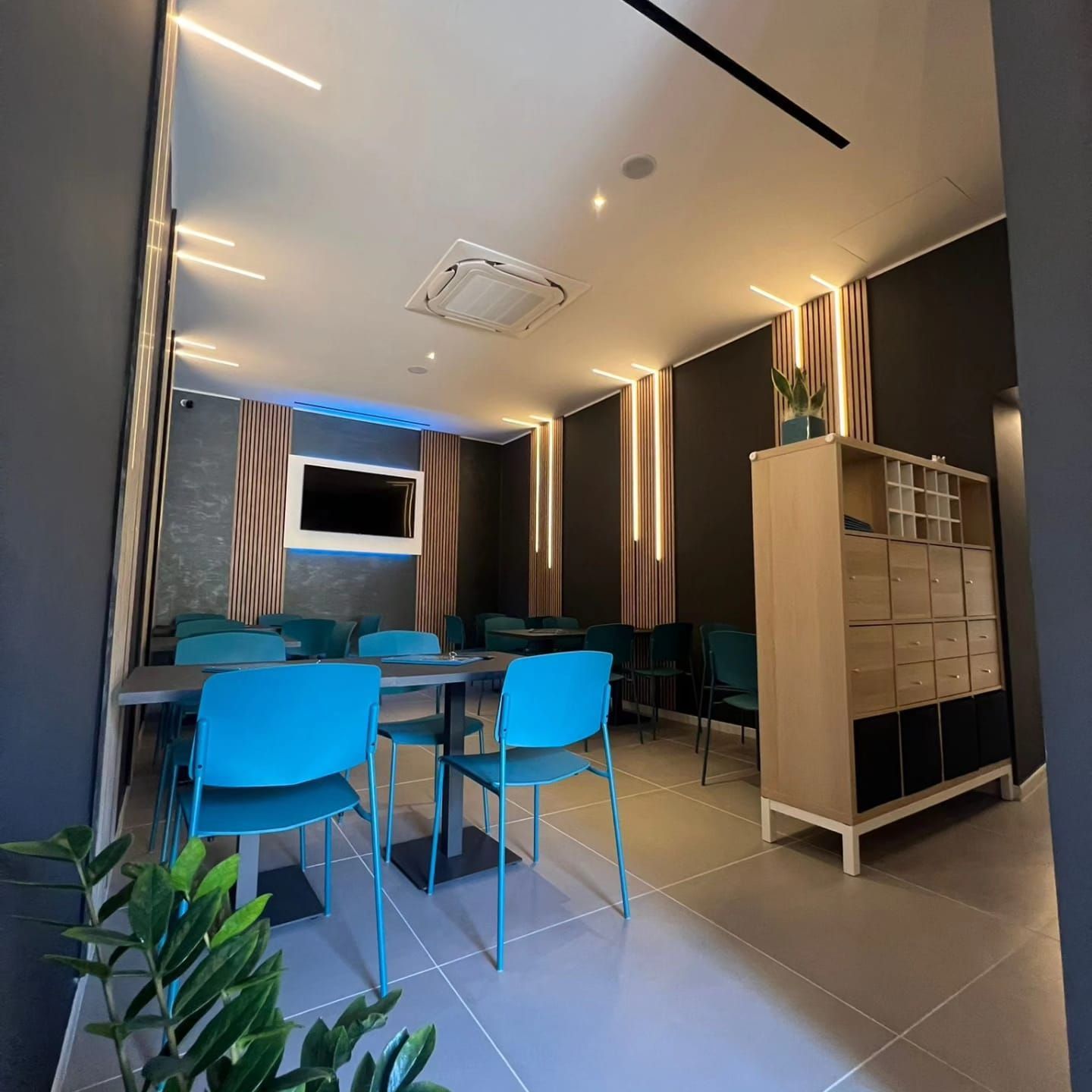 Moderna sala riunioni con sedie color verde acqua, un tavolo e un mobiletto.