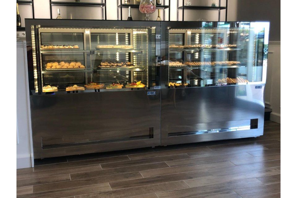 Vetrina refrigerata in acciaio inox piena di pasticcini, in una panetteria.