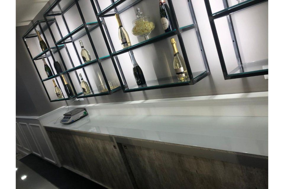 Scaffali con bottiglie, sopra un bancone in legno in un negozio.