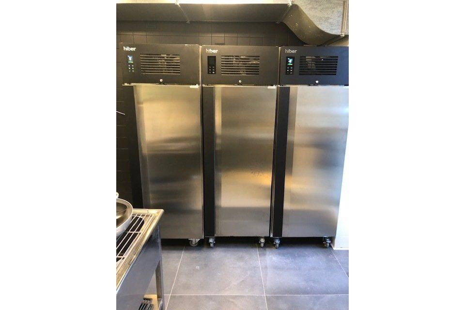 Tre frigoriferi commerciali in acciaio inox in una cucina.