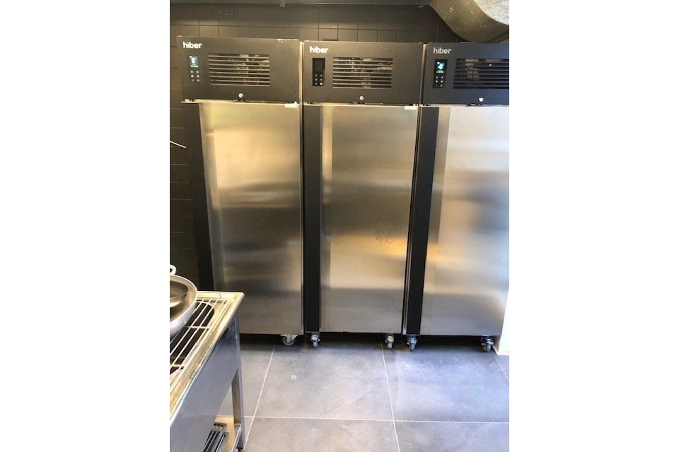 Tre frigoriferi in acciaio inossidabile affiancati in una cucina commerciale.