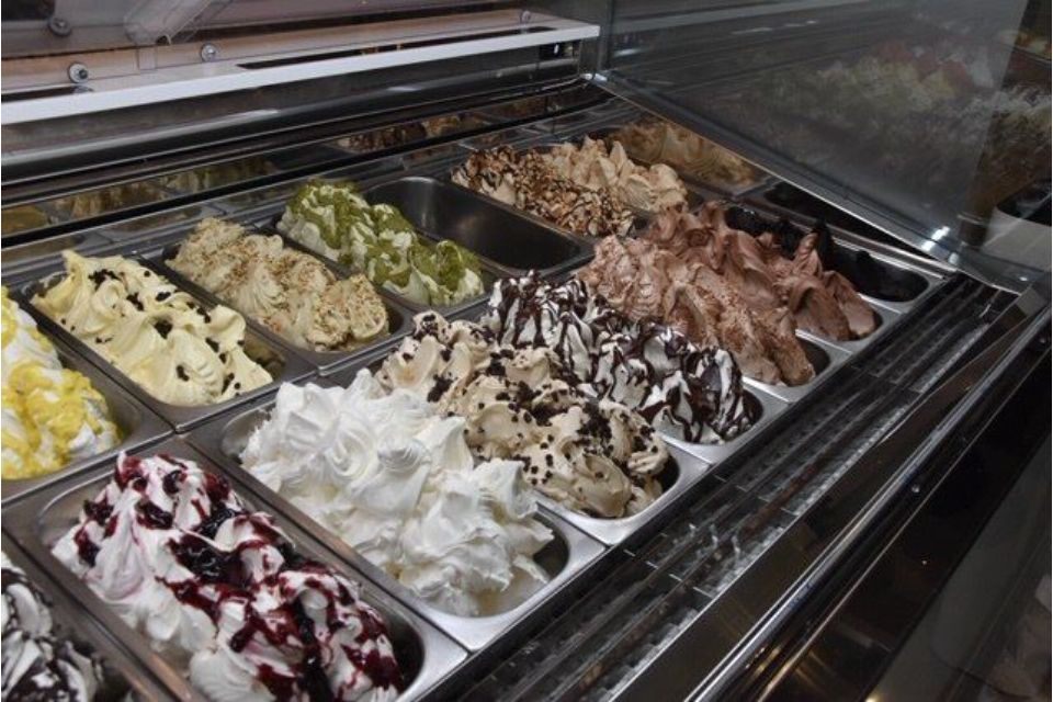 Vetrina per gelati con vari gusti, come cioccolato, pistacchio e vaniglia.
