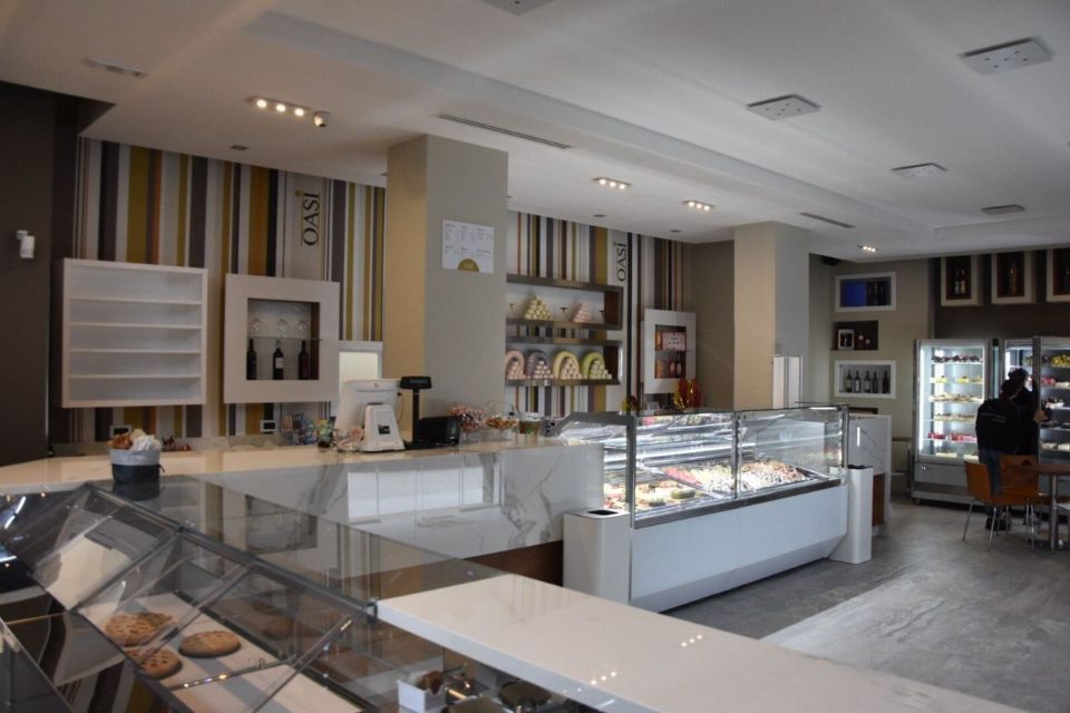 Interno di un bar con vetrine, bancone e parete a strisce.