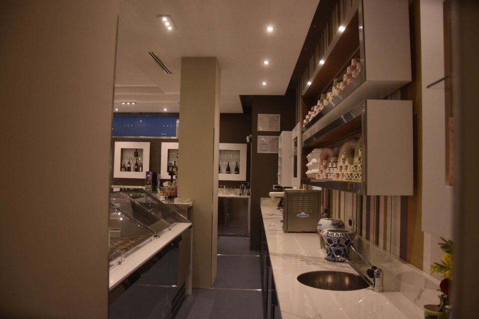 Vista interna di un bar con bancone, lavandino e scaffali con bicchieri.