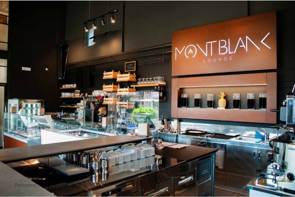 Interno di una Montblanc Lounge: bar, esposizione di profumi, pareti scure e dettagli in legno.
