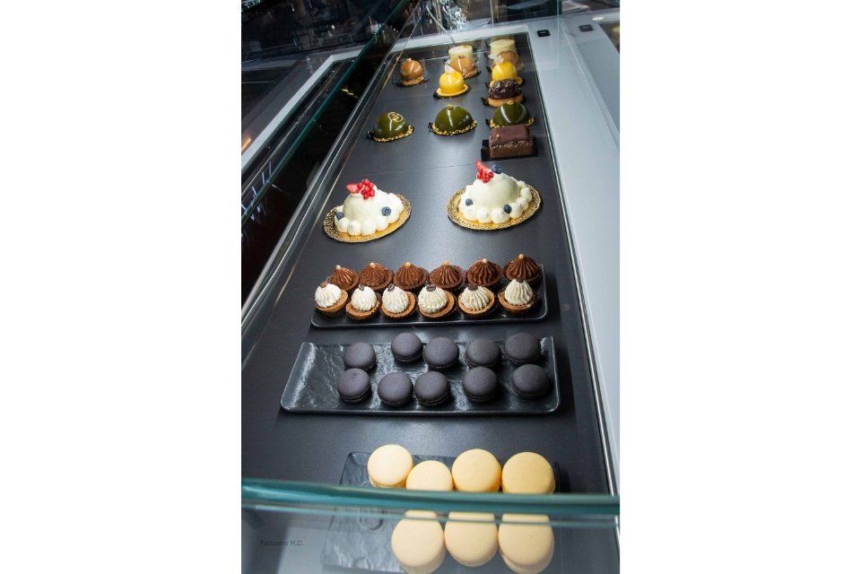 Vetrina con vari tipi di pasticcini colorati, tra cui crostate, macaron e tortine.