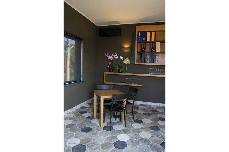 Una piccola sala da pranzo con pareti scure, mobili in legno e pavimento con motivi esagonali.