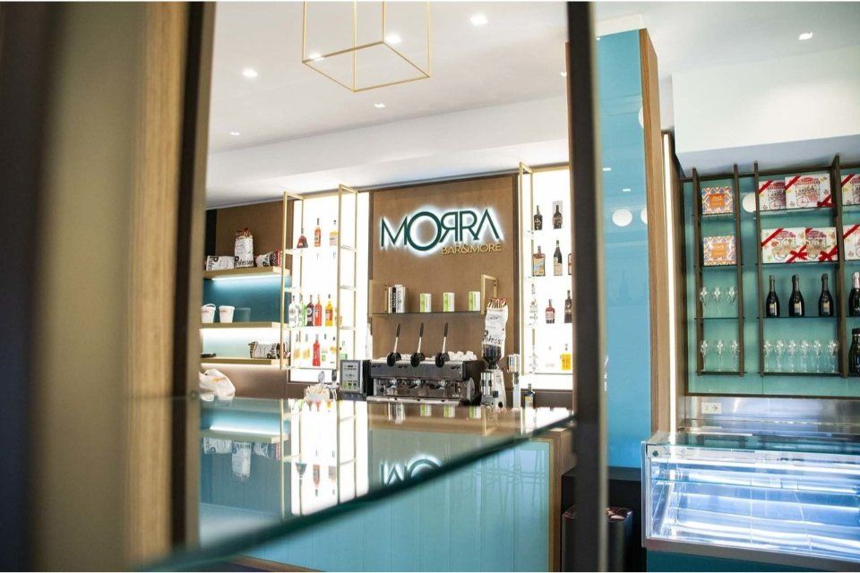 Interno di un moderno bar con dettagli blu e oro, in cui vengono esposti drink e prodotti.