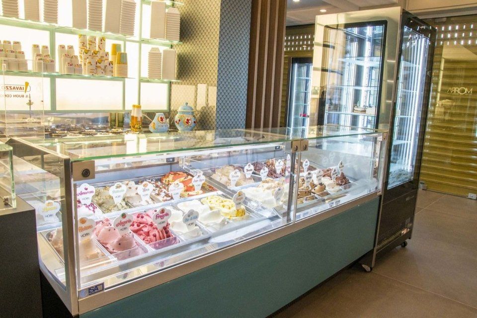 Vetrina per gelati in un negozio; sono visibili vari gusti di gelato colorati.