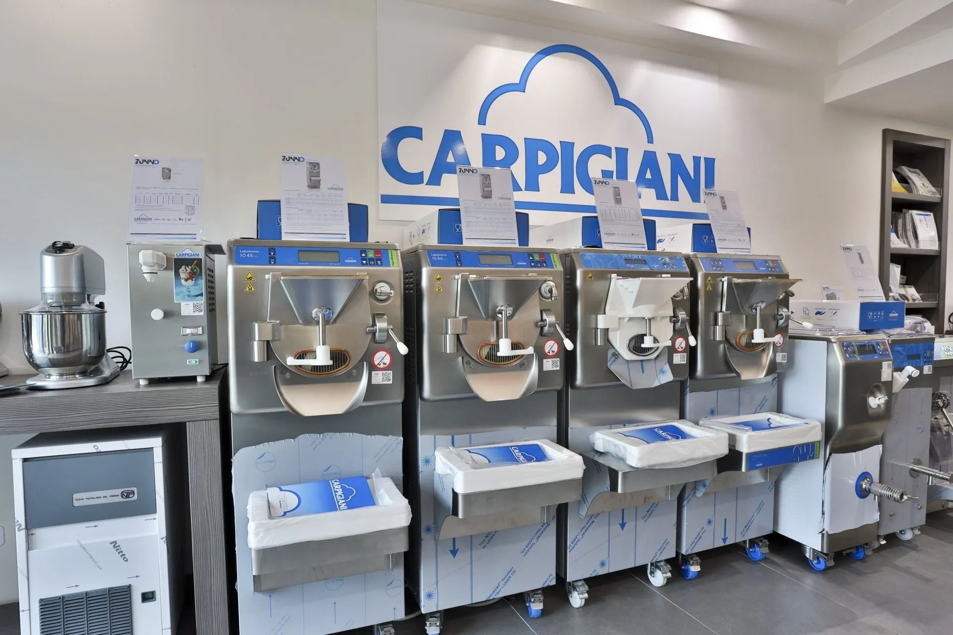 Esposizione di macchine per il gelato Carpigiani in un negozio, con il nome del marchio in blu sopra gli elettrodomestici.