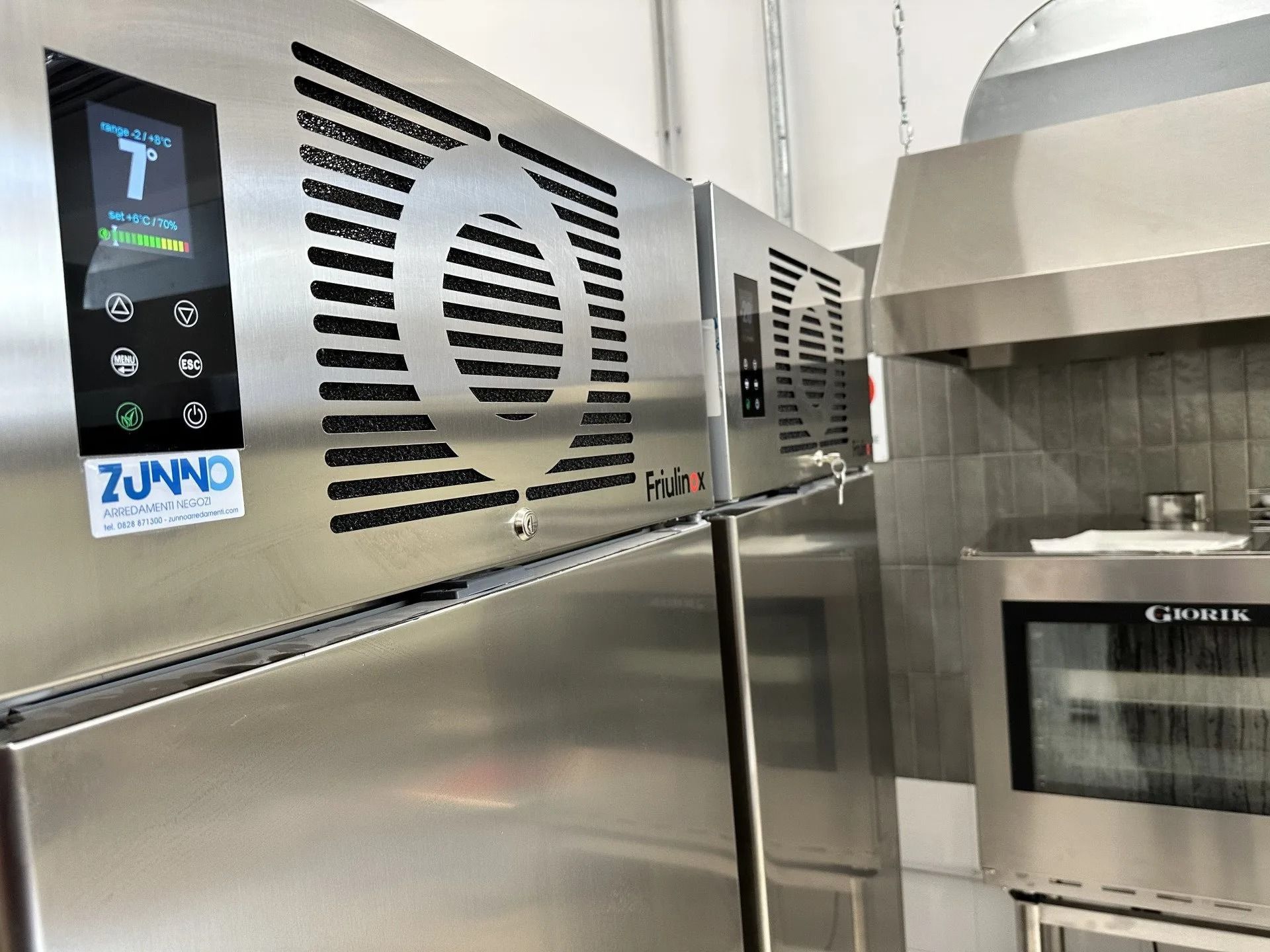 Attrezzature da cucina commerciali in acciaio inossidabile, tra cui un abbattitore di temperatura Zumo, un forno e una cappa aspirante.