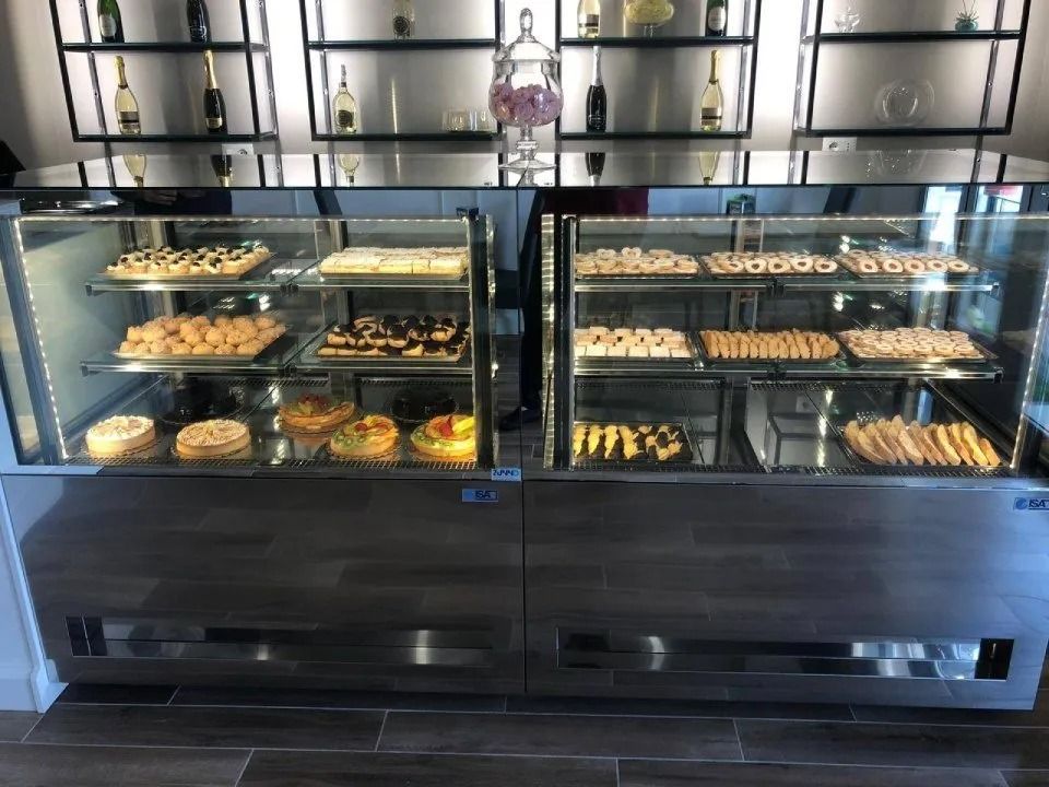Vetrina di pasticceria piena di vari prodotti da forno in un ambiente da panetteria.