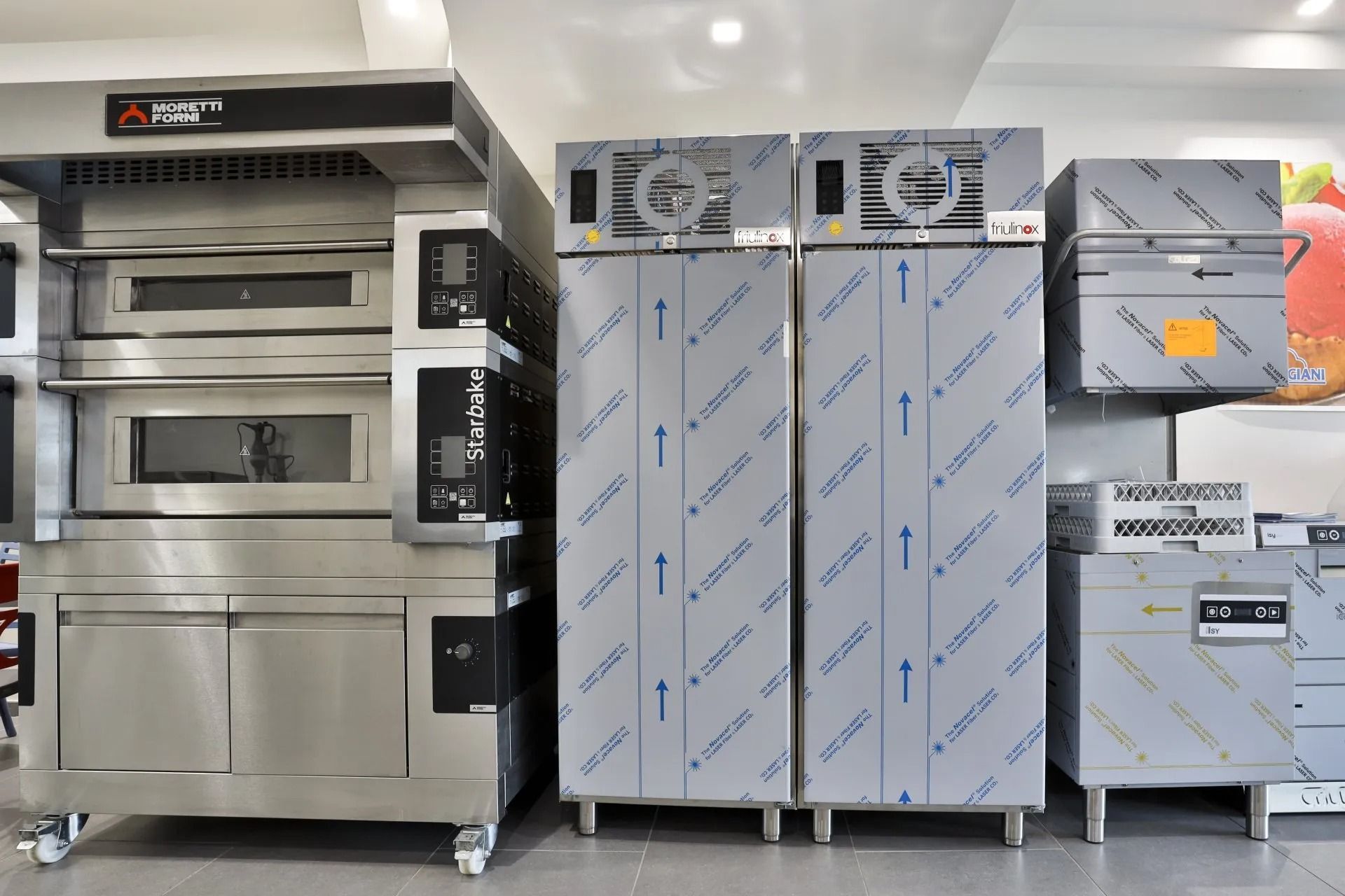 Attrezzatura da cucina commerciale: forno, congelatori e un piccolo elettrodomestico da banco in un ambiente da negozio.