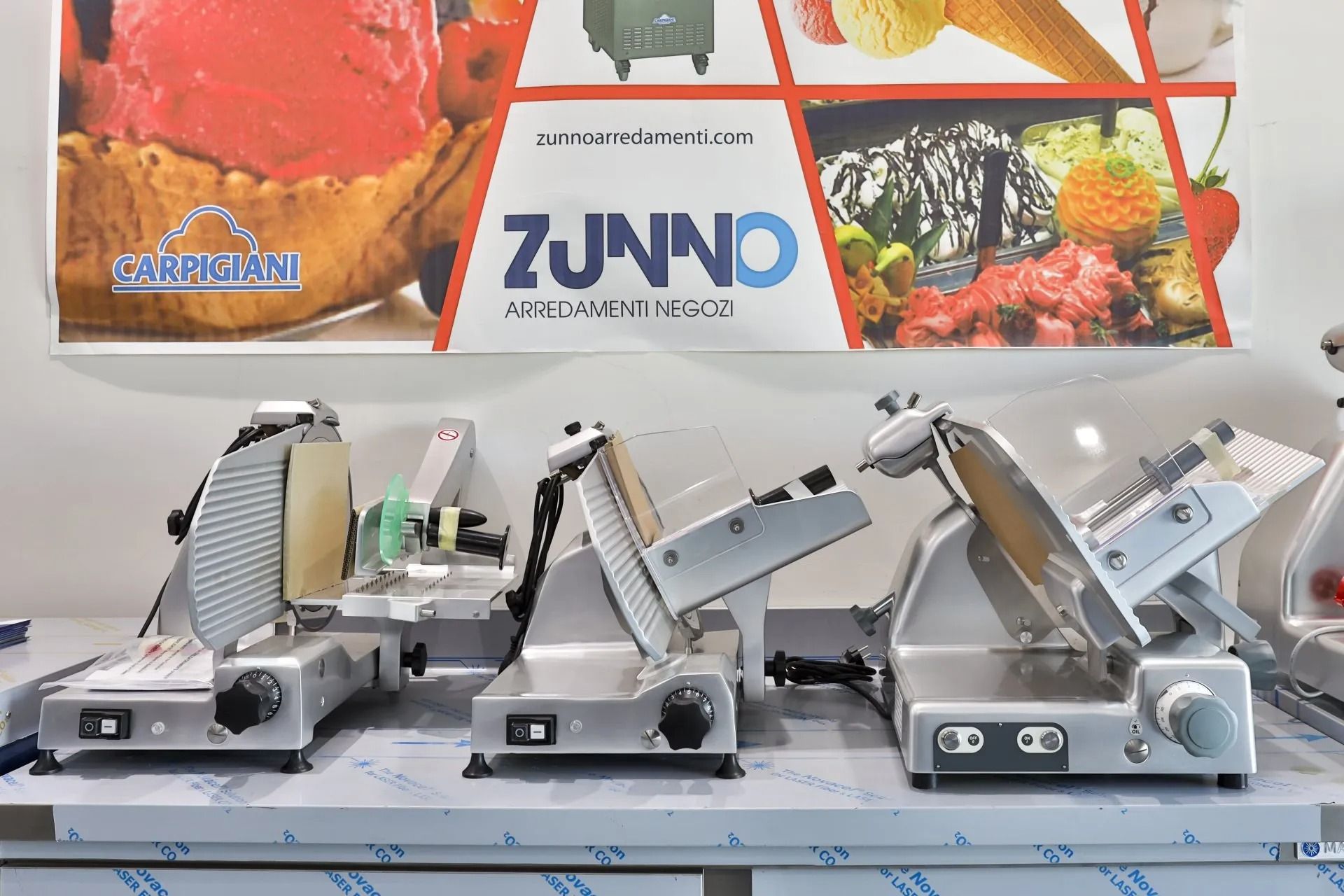 Affettatrici in esposizione con uno striscione della Zunno Food Equipment Services sullo sfondo.