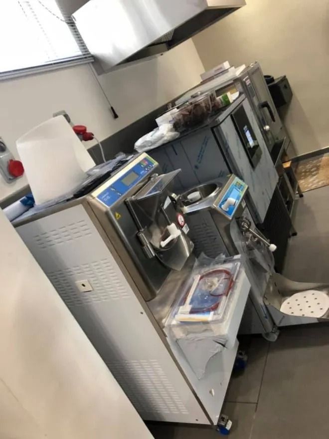 Attrezzature per cucine commerciali: macchina per il gelato, forno, cappa di aspirazione, superfici in acciaio inox.