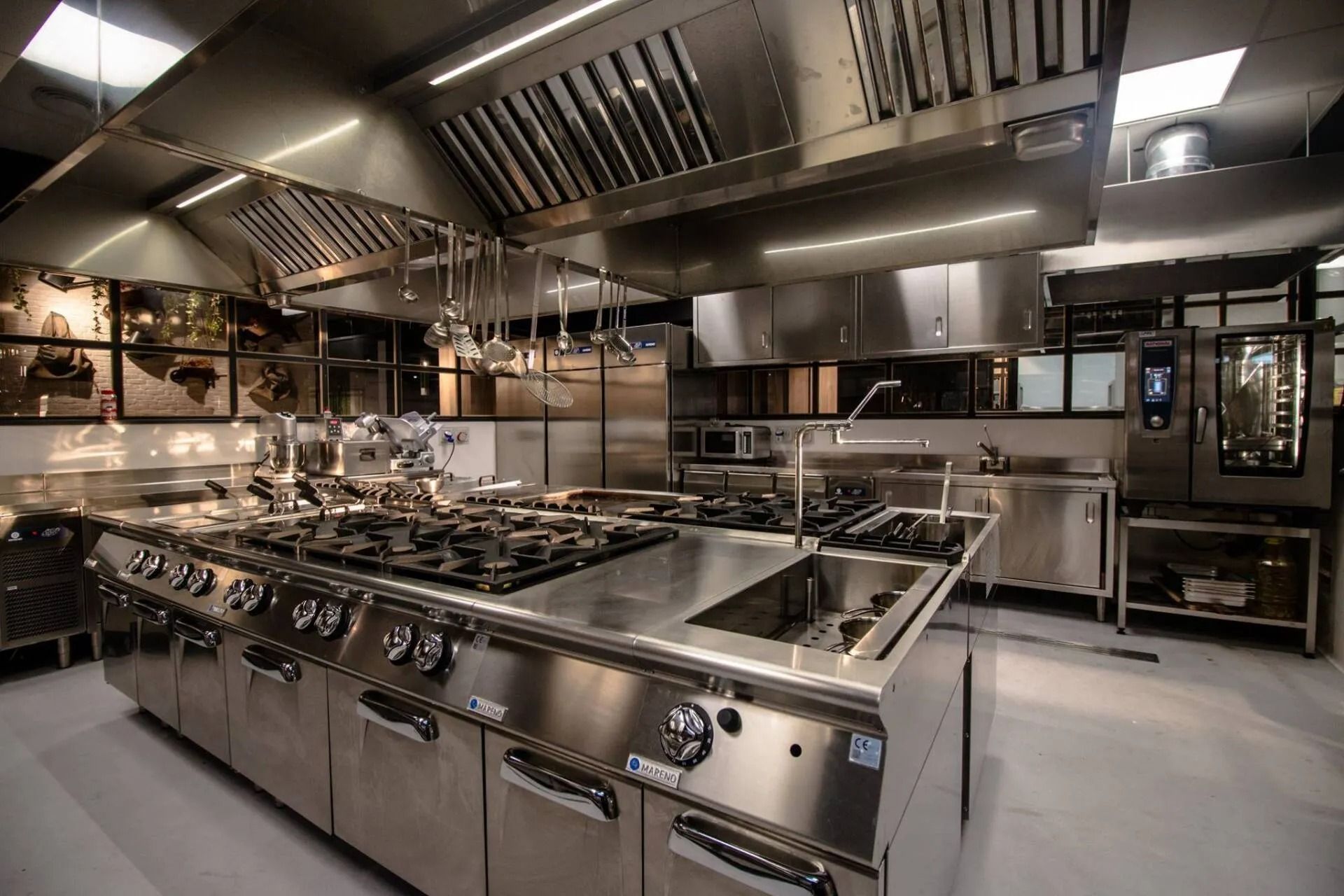 Cucina commerciale con elettrodomestici in acciaio inossidabile e cappa aspirante.
