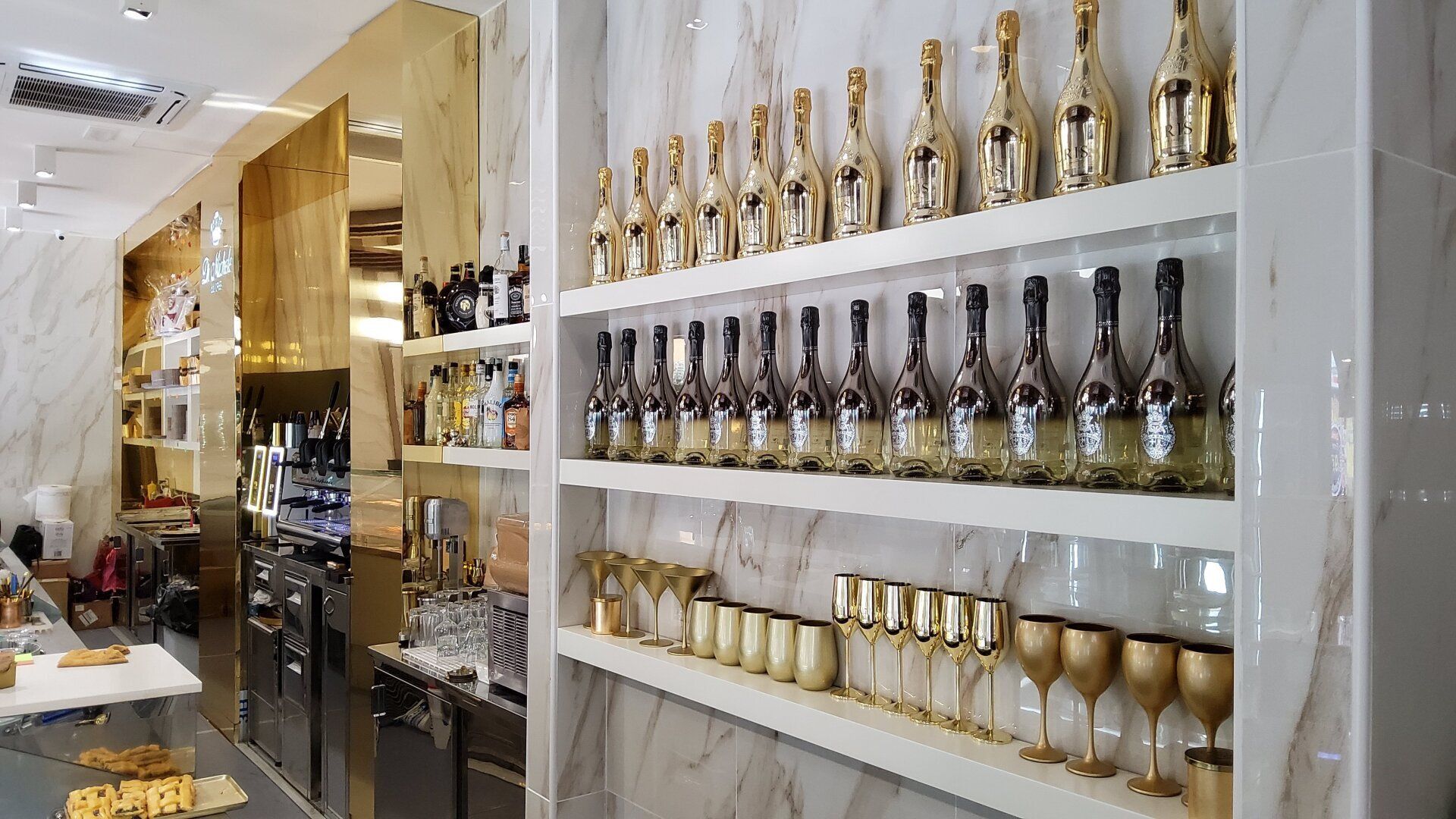 Scaffali che espongono bottiglie e bicchieri dorati e neri in un negozio moderno e ben illuminato.