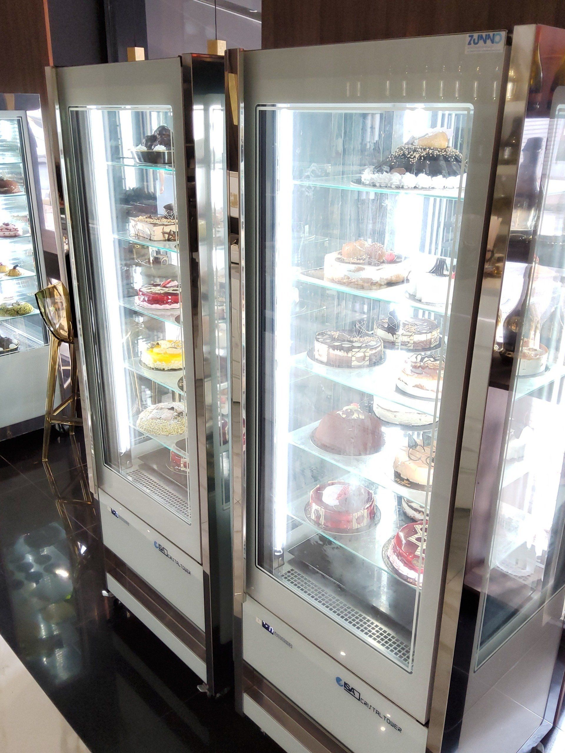 Due vetrine illuminate piene di torte. Rifiniture argentate, illuminazione intensa, interno.