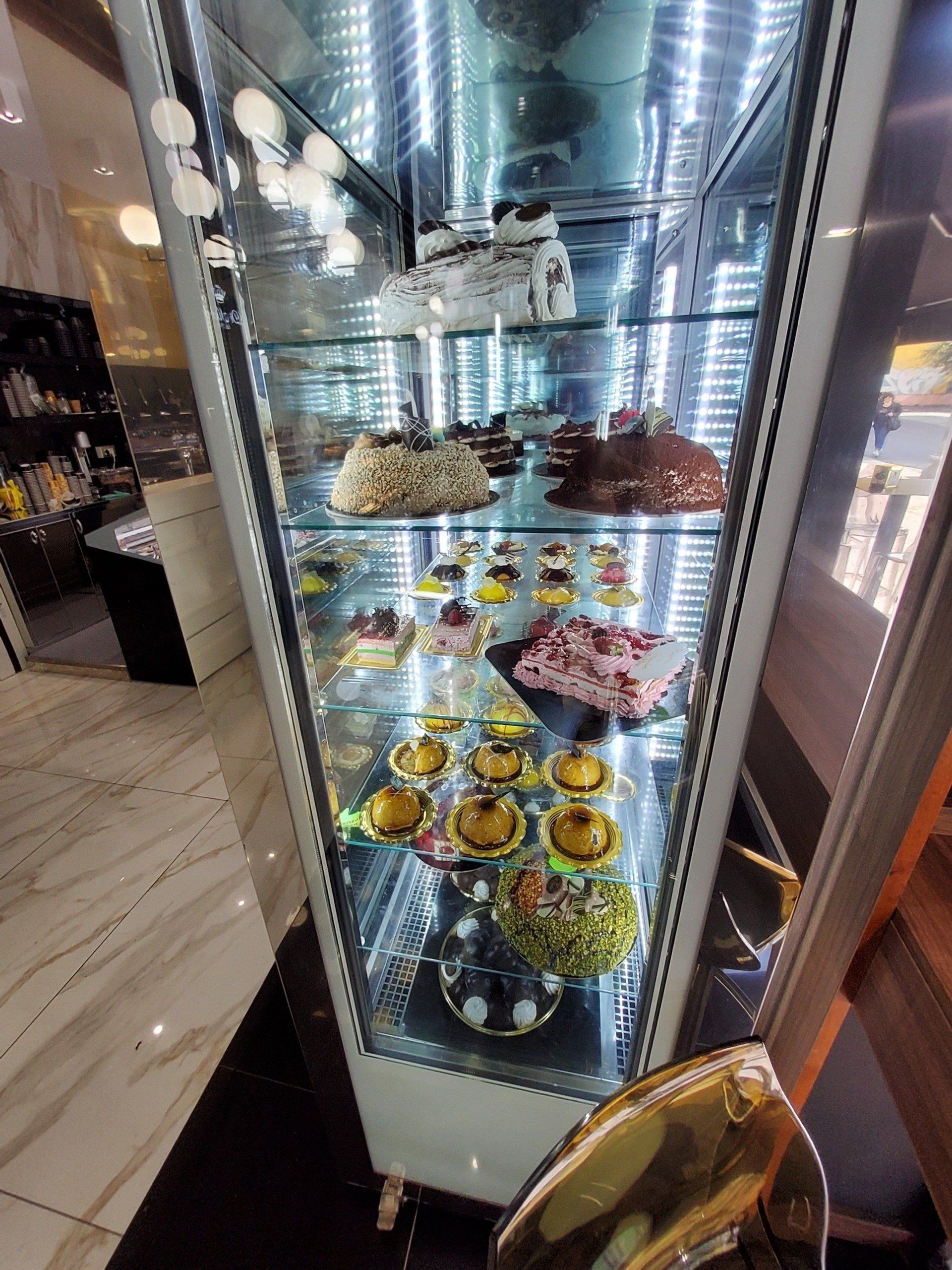 Vetrina di vetro piena di vari dessert, torte e pasticcini in una panetteria.