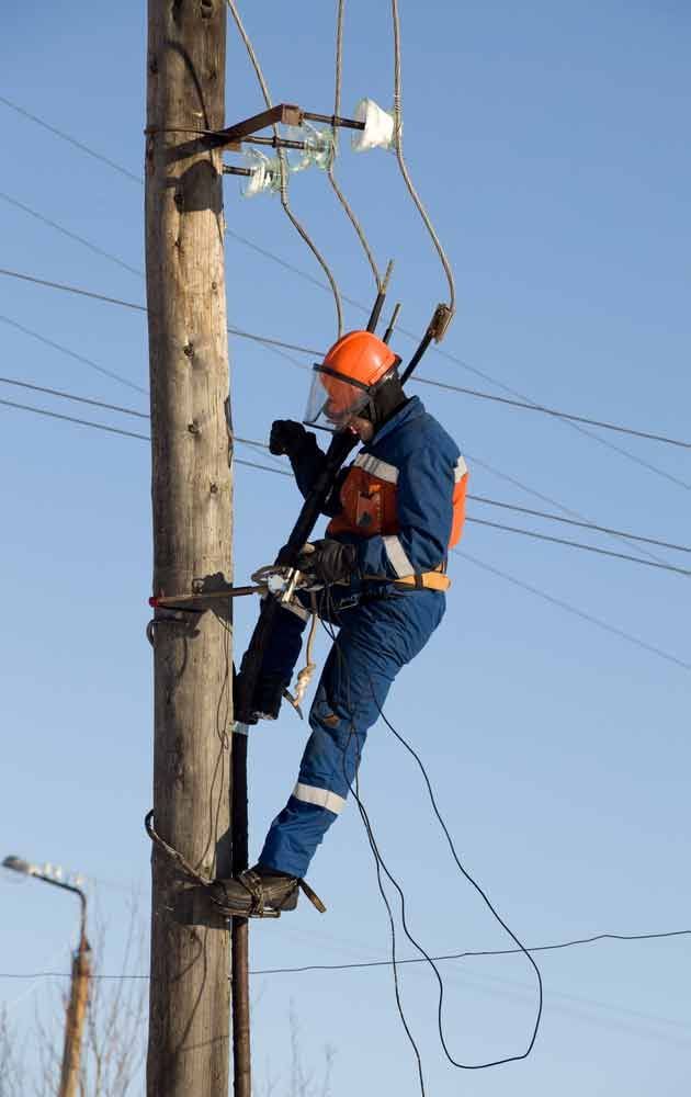 Electrician in Blue Overalls Working at Height with Wires — Level 2 Electrician in Toukley, NSW