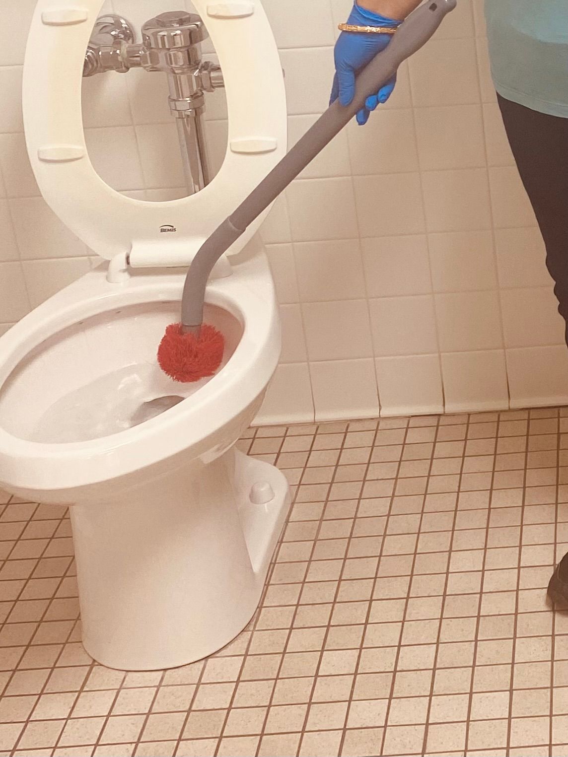A person is cleaning a toilet with a plunger