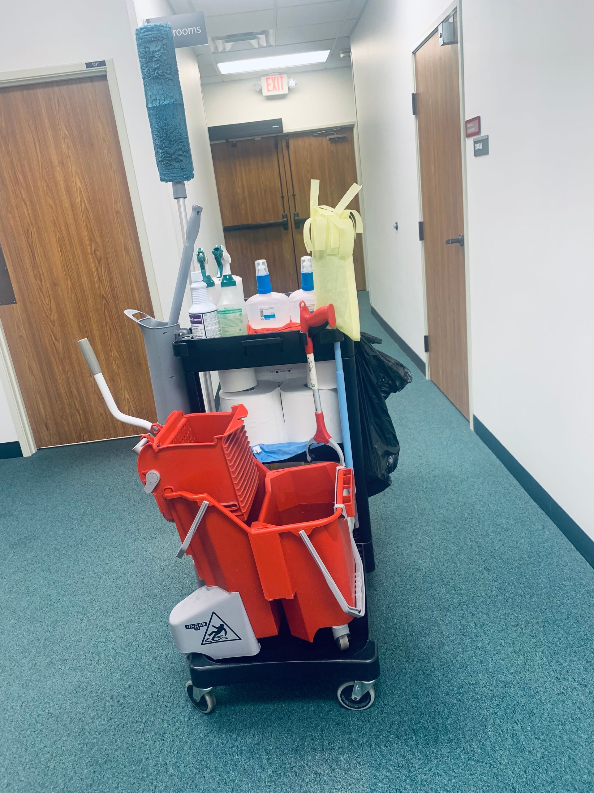 A cleaning cart in a hallway with a mop and buckets