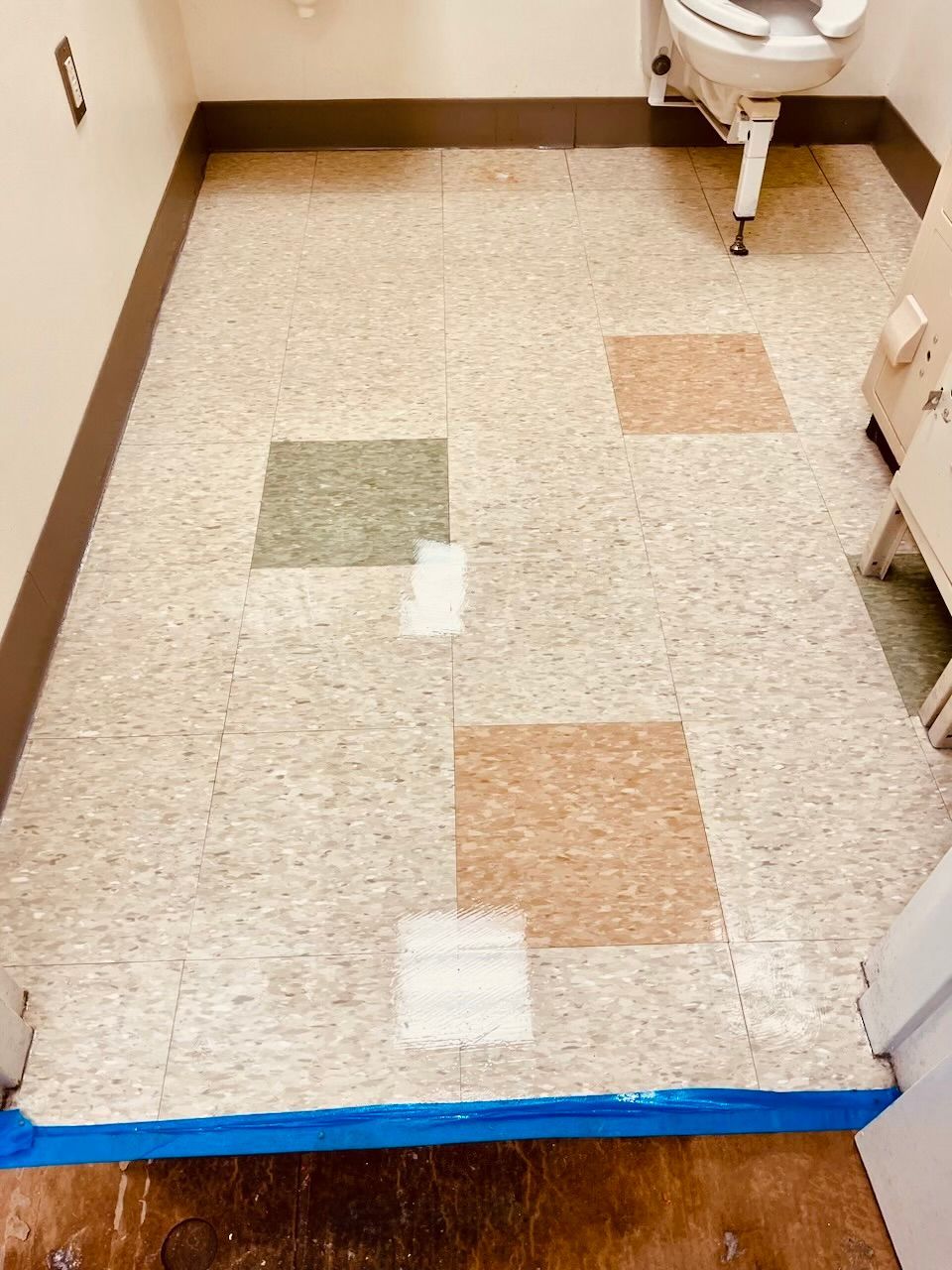 A bathroom with a tiled floor and a toilet.