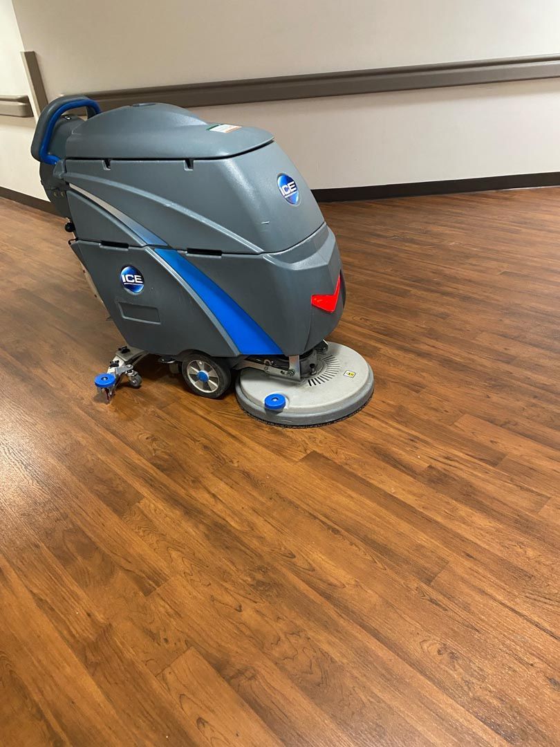 A machine is cleaning a wooden floor in a hallway.
