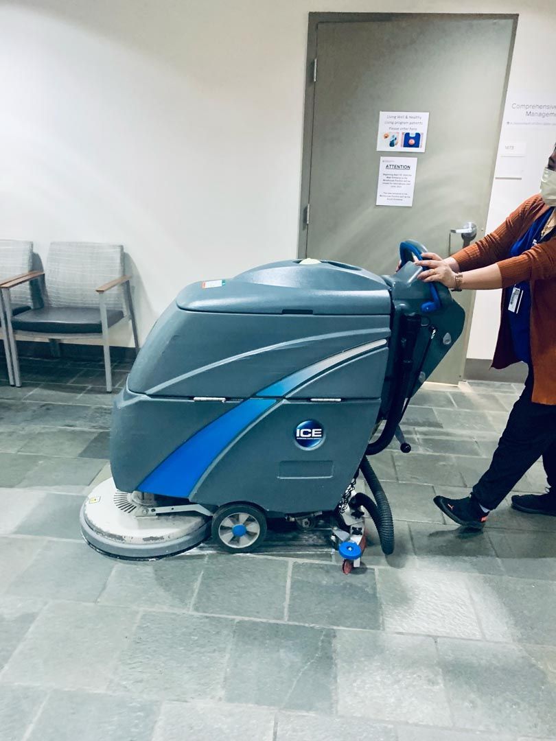 A woman is pushing a machine on a tiled floor.