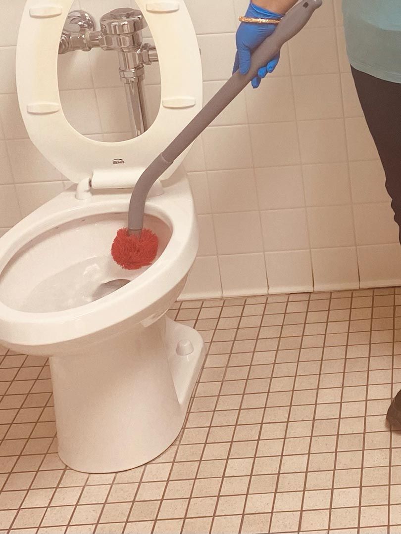 A person is cleaning a toilet with a brush