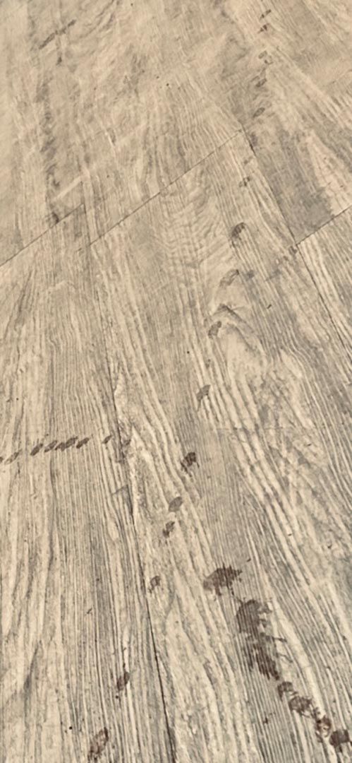 A close up of a wooden floor with a tire track on it.