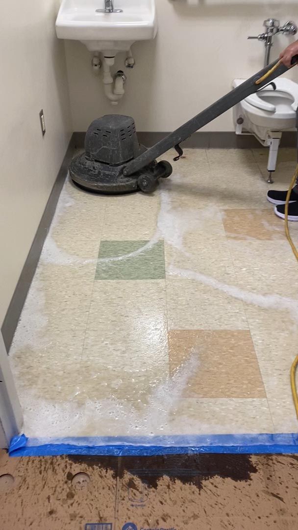 A person is cleaning a bathroom floor with a vacuum cleaner.