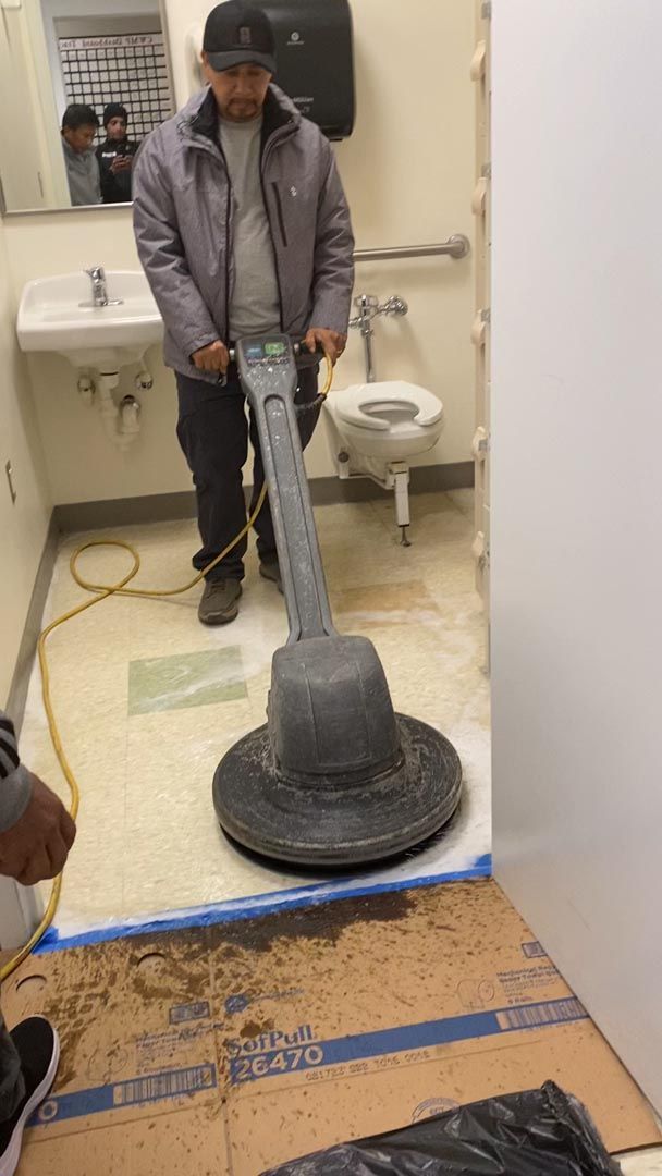 A man is cleaning the floor of a bathroom with a machine.