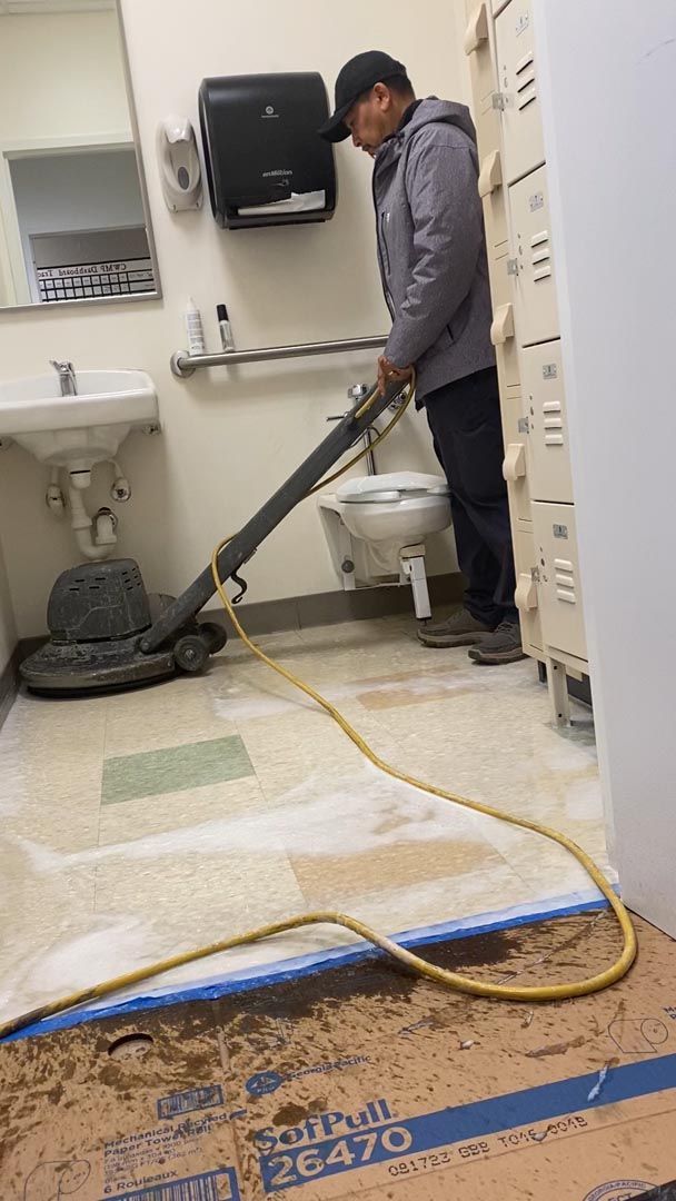A man is cleaning a bathroom floor with a vacuum cleaner.