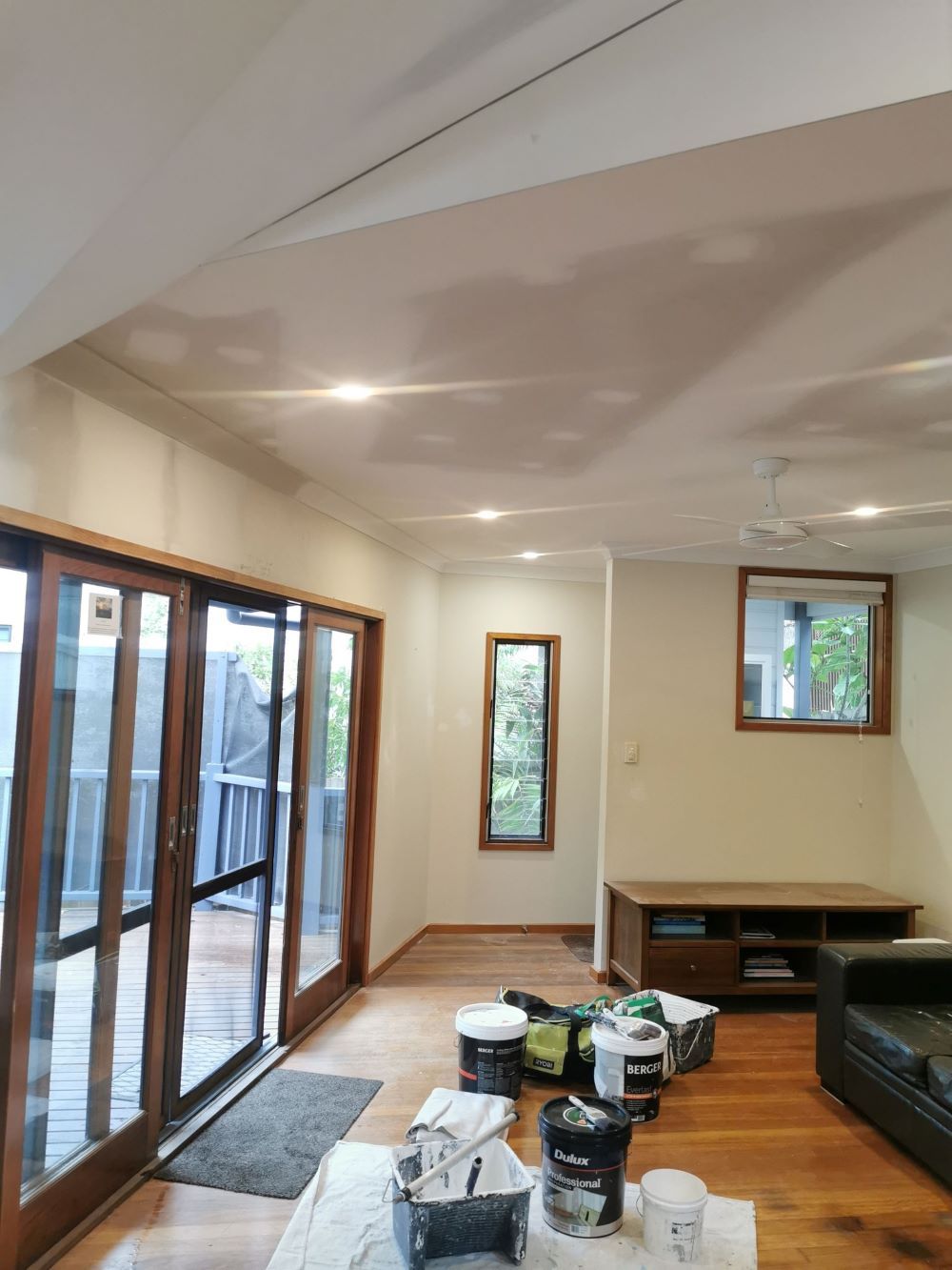 A Living Room With a Lot of Windows and Painting Buckets on the Floor — Eva Professional Painting in Robina, QLD