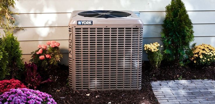 A york air conditioner is sitting in a garden surrounded by flowers.