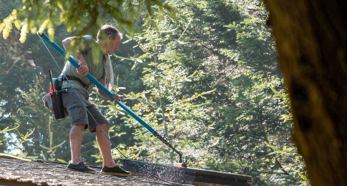 A man is cleaning a roof from moss in Stoke-on-Trent. Photo by Home Rejuvenate.